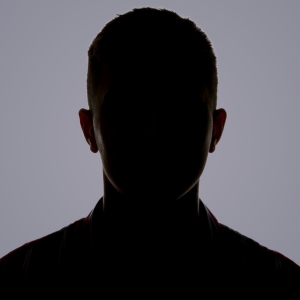 Darkened silhouette of a man against a purple-gray background