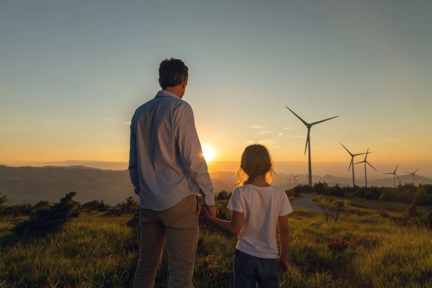 Family looking at sunset and wind turbines